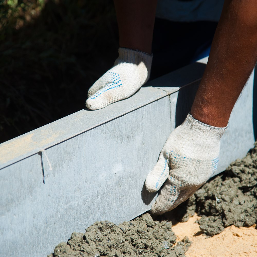 adult-constructing-edging-with-cement-and-tools Adult constructing edging with cement and tools