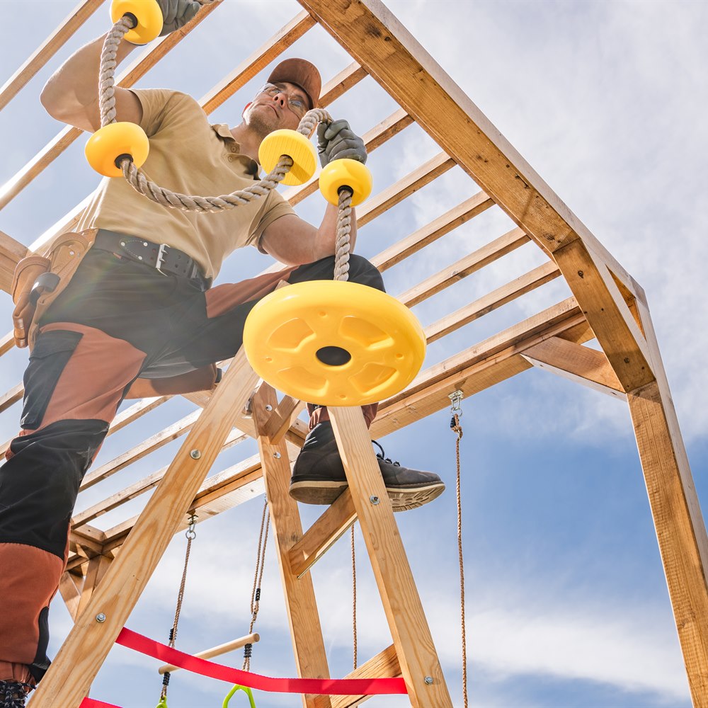 Adult male constructing a wooden playset outdoors