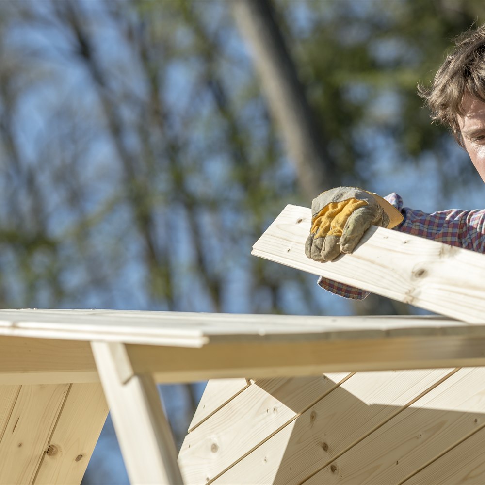 Adult man builds wood structure outdoors