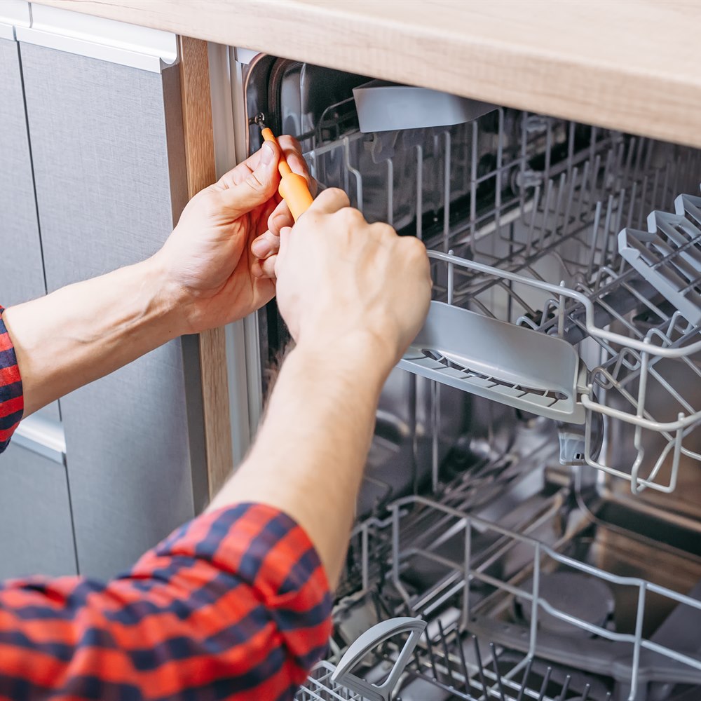 Adult repairing dishwasher in home kitchen