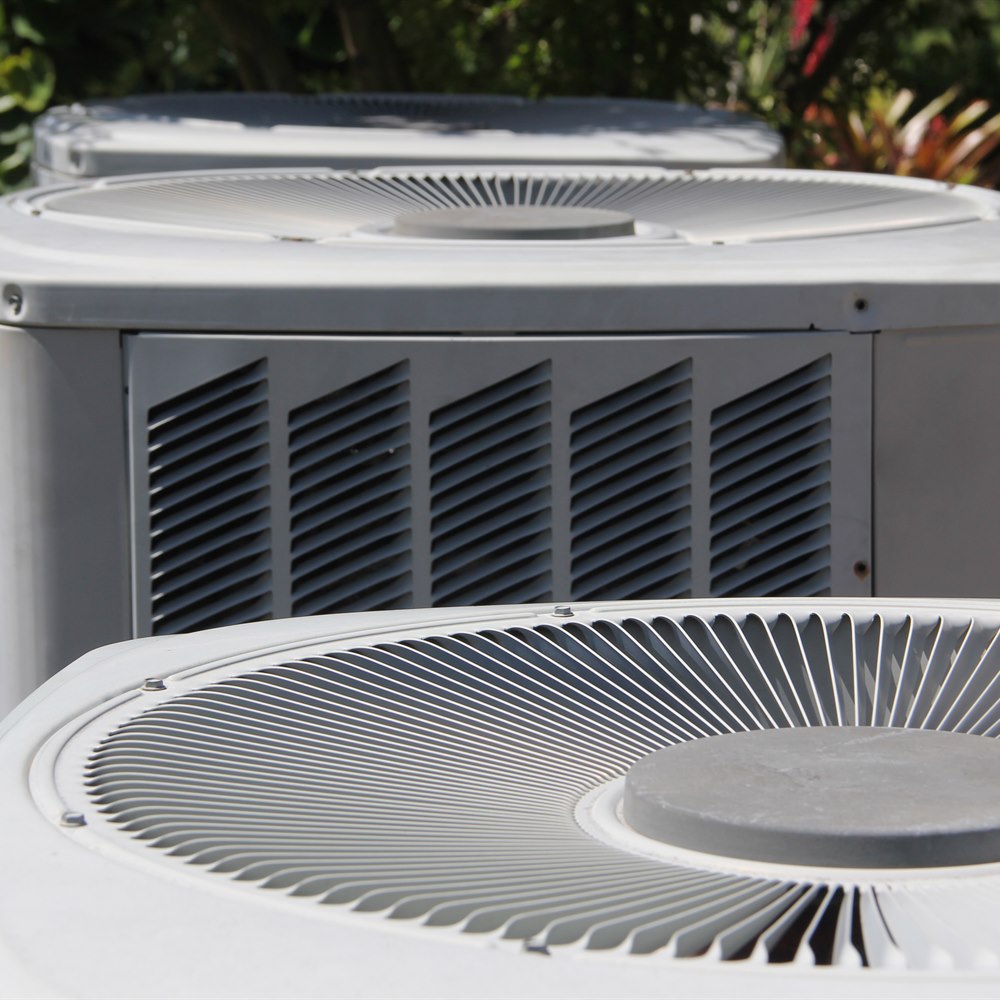 Air conditioner units near green foliage