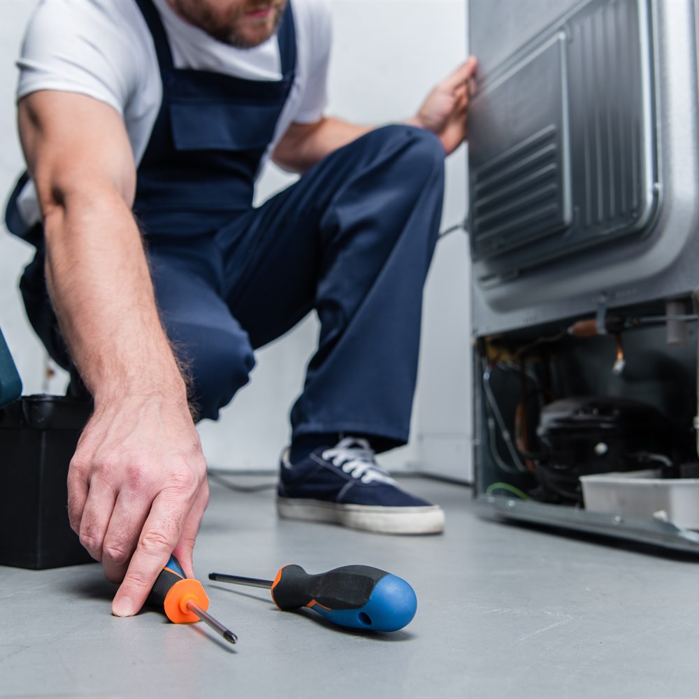 Appliance repair specialist fixing refrigerator