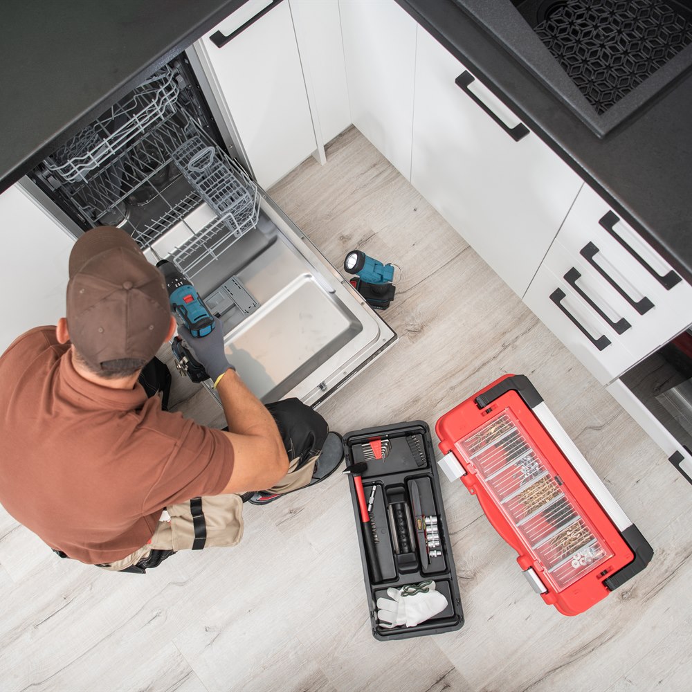 Appliance repairman fixing dishwasher