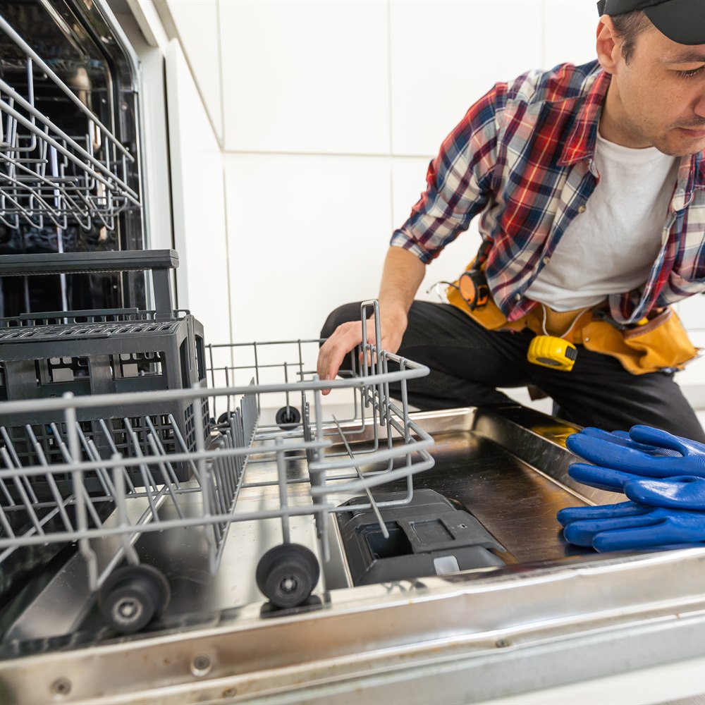 appliance-repairman-repairing-dishwasher-in-kitche Appliance repairman repairing dishwasher in kitchen