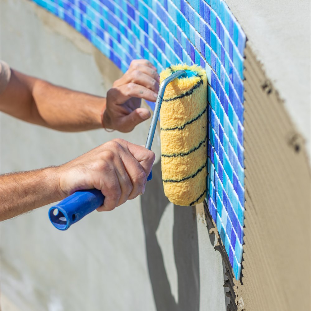 Applying yellow foam on blue tile pool