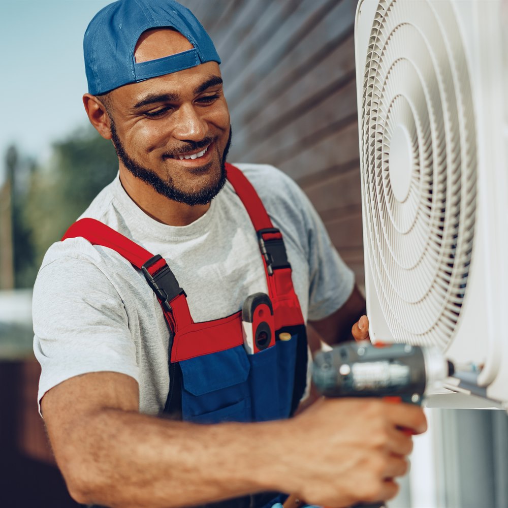 Bearded man repairing air conditioner outside building