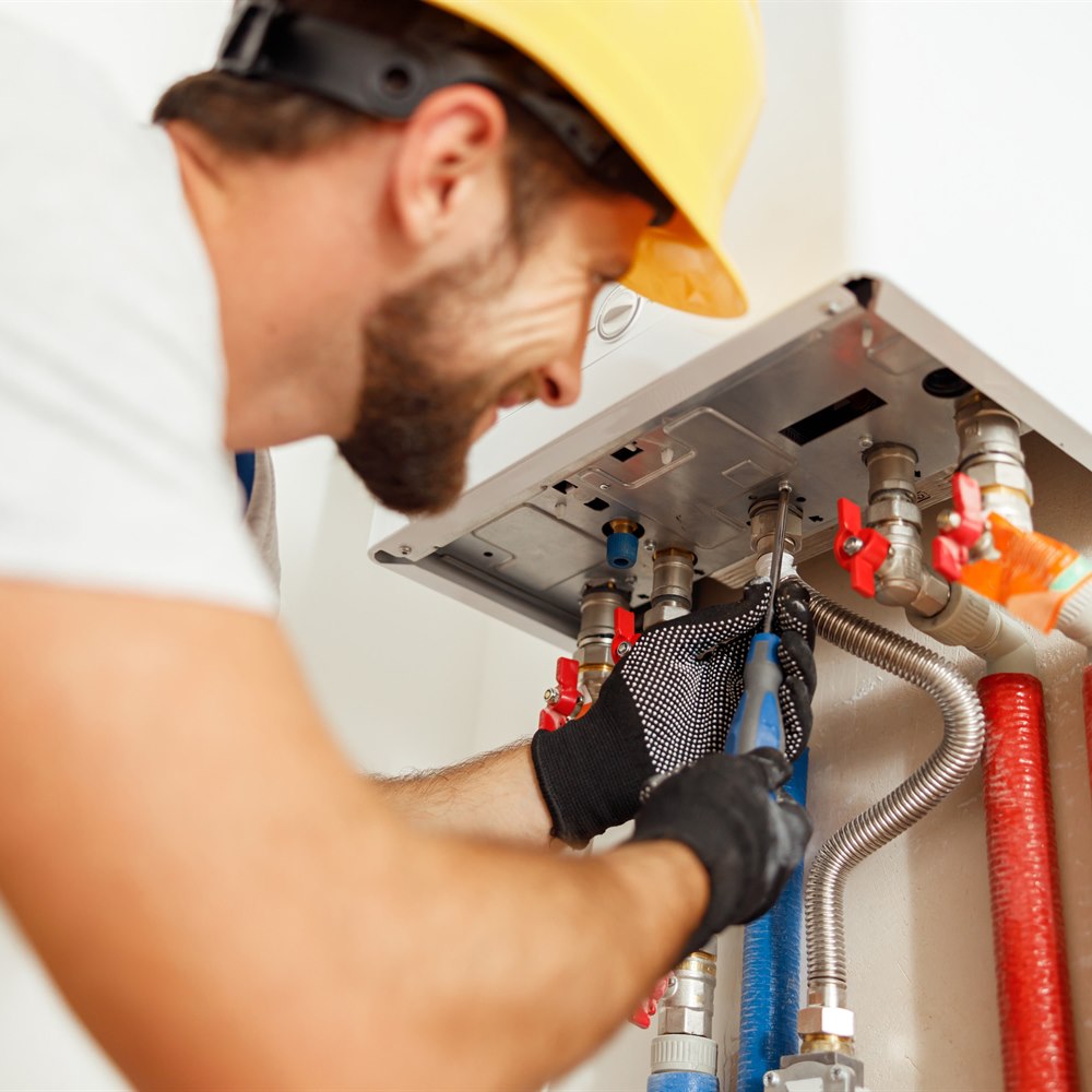 Bearded technician repairing water heater in home