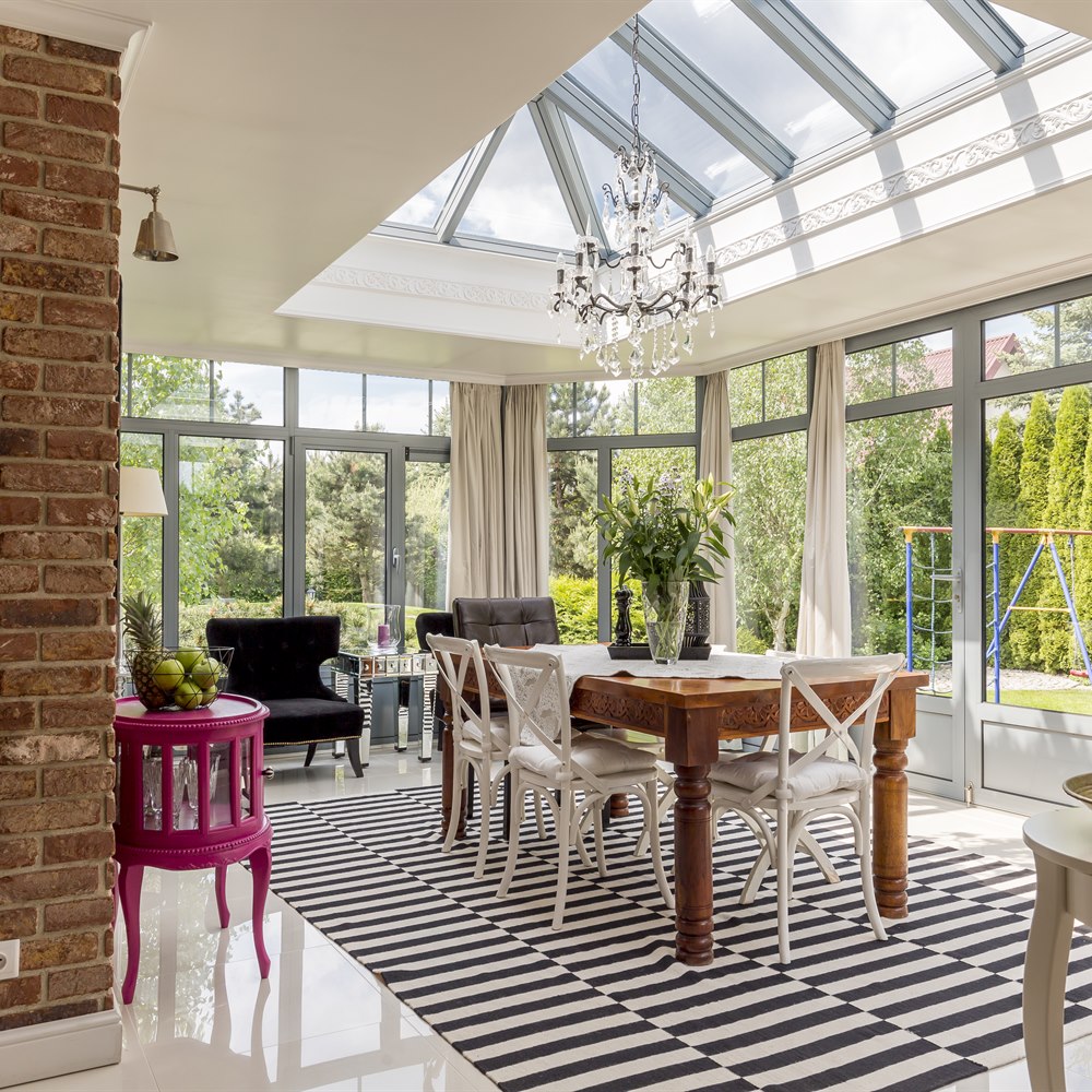 Bright sunroom interior with table and striped rug