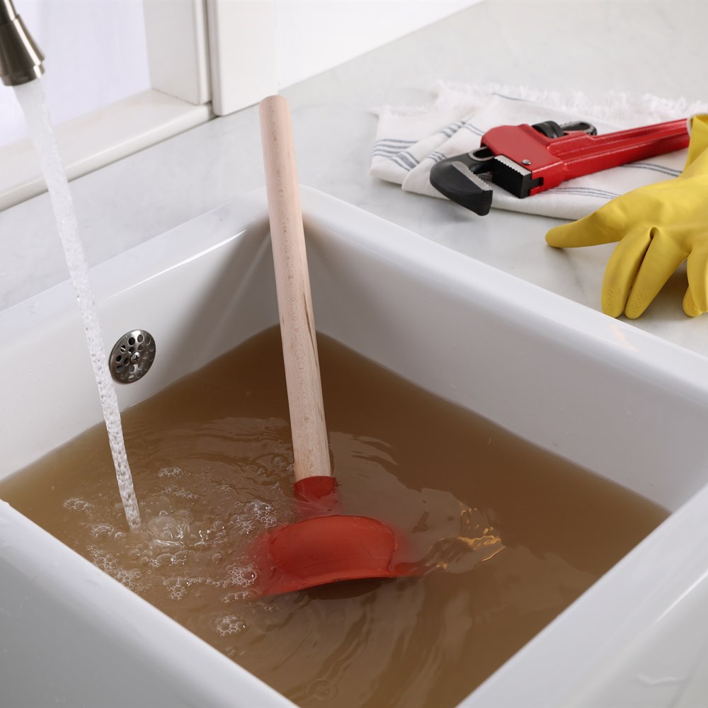 Clogged sink with plumber tools and dirty water
