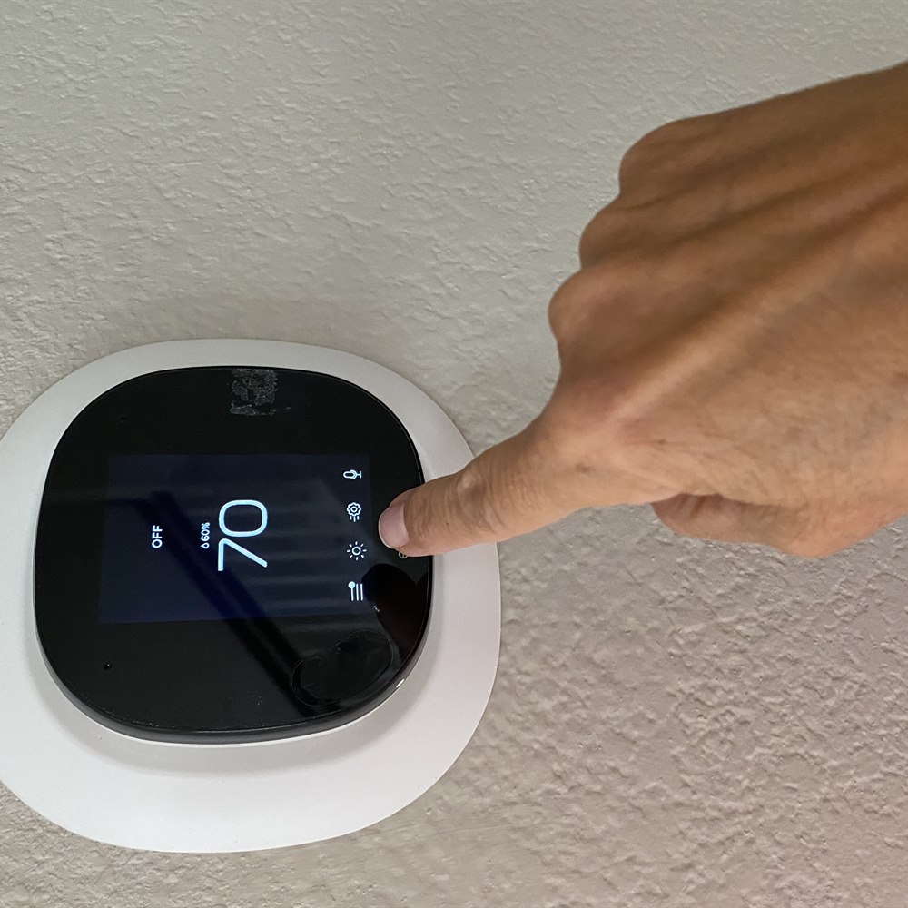 Close up of hand touching smart thermostat