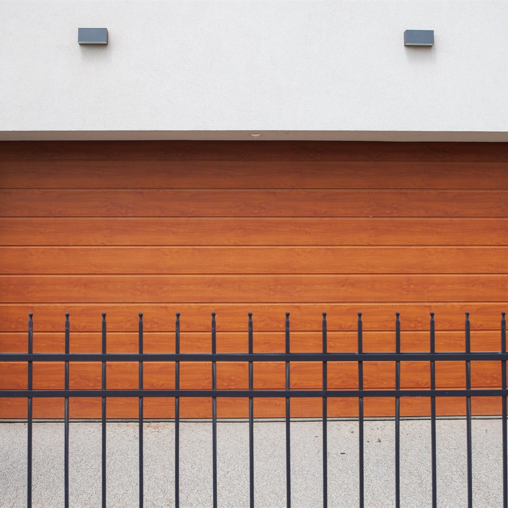 Closed wooden garage door behind a metal fence
