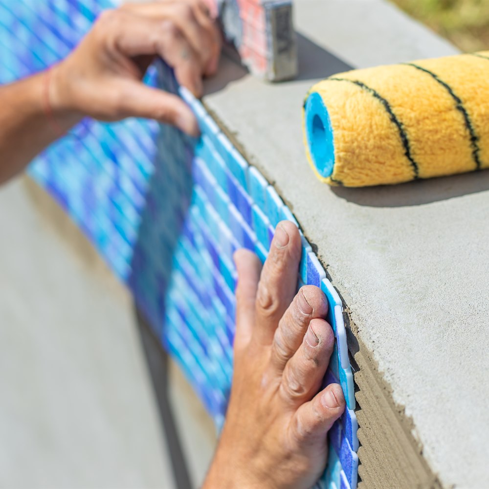 Construction worker adds tile to concrete wall