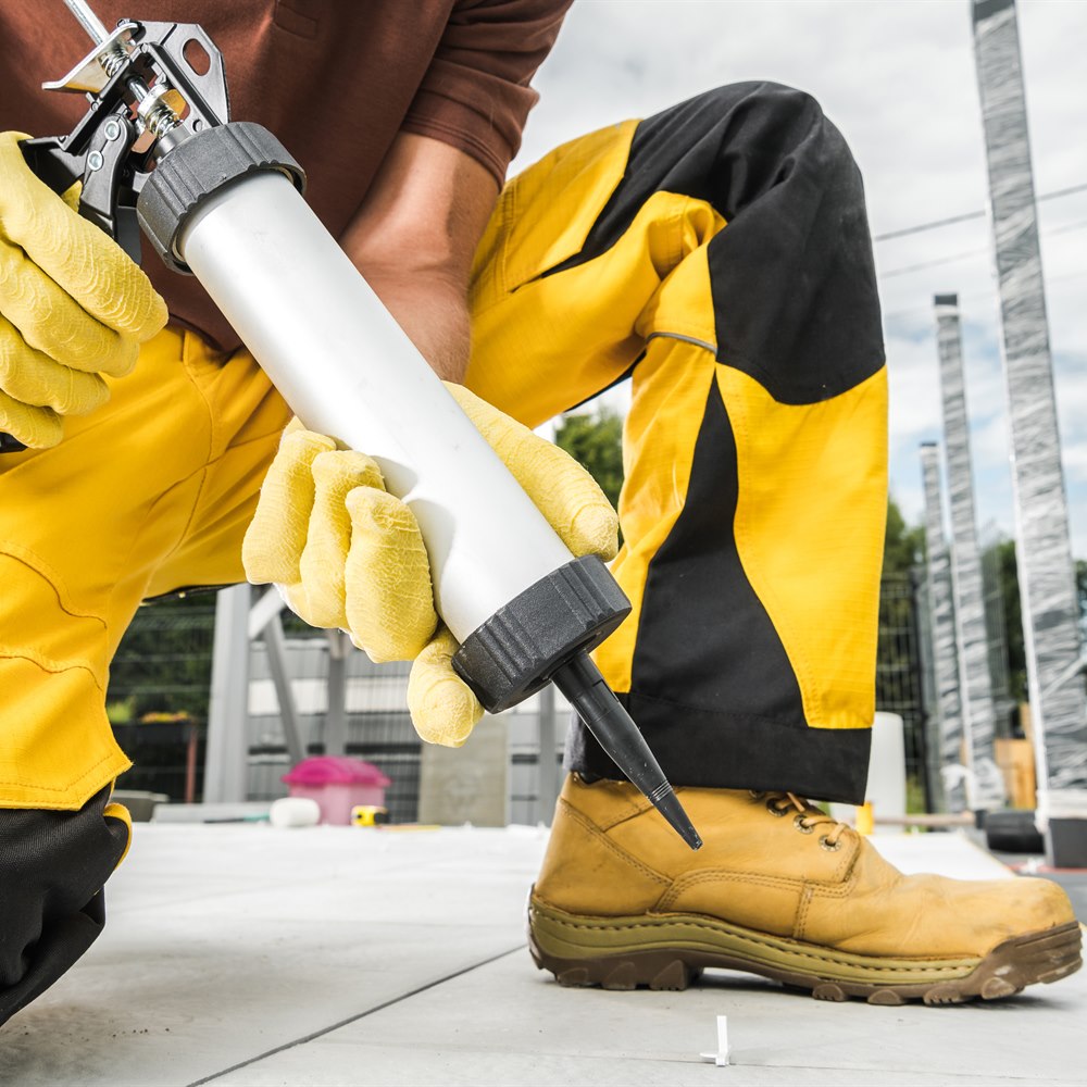 Construction worker applies adhesive on floor tile