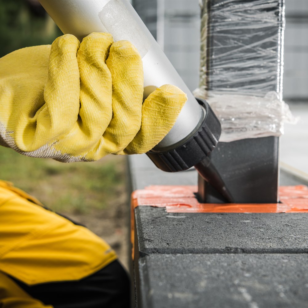 Construction worker applying sealant to blocks