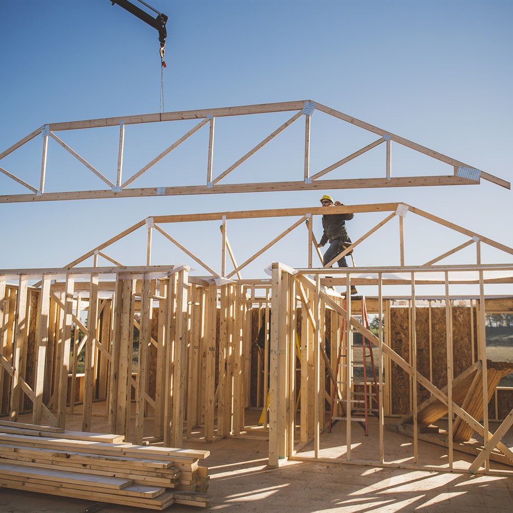 Construction worker assembles a wood frame building