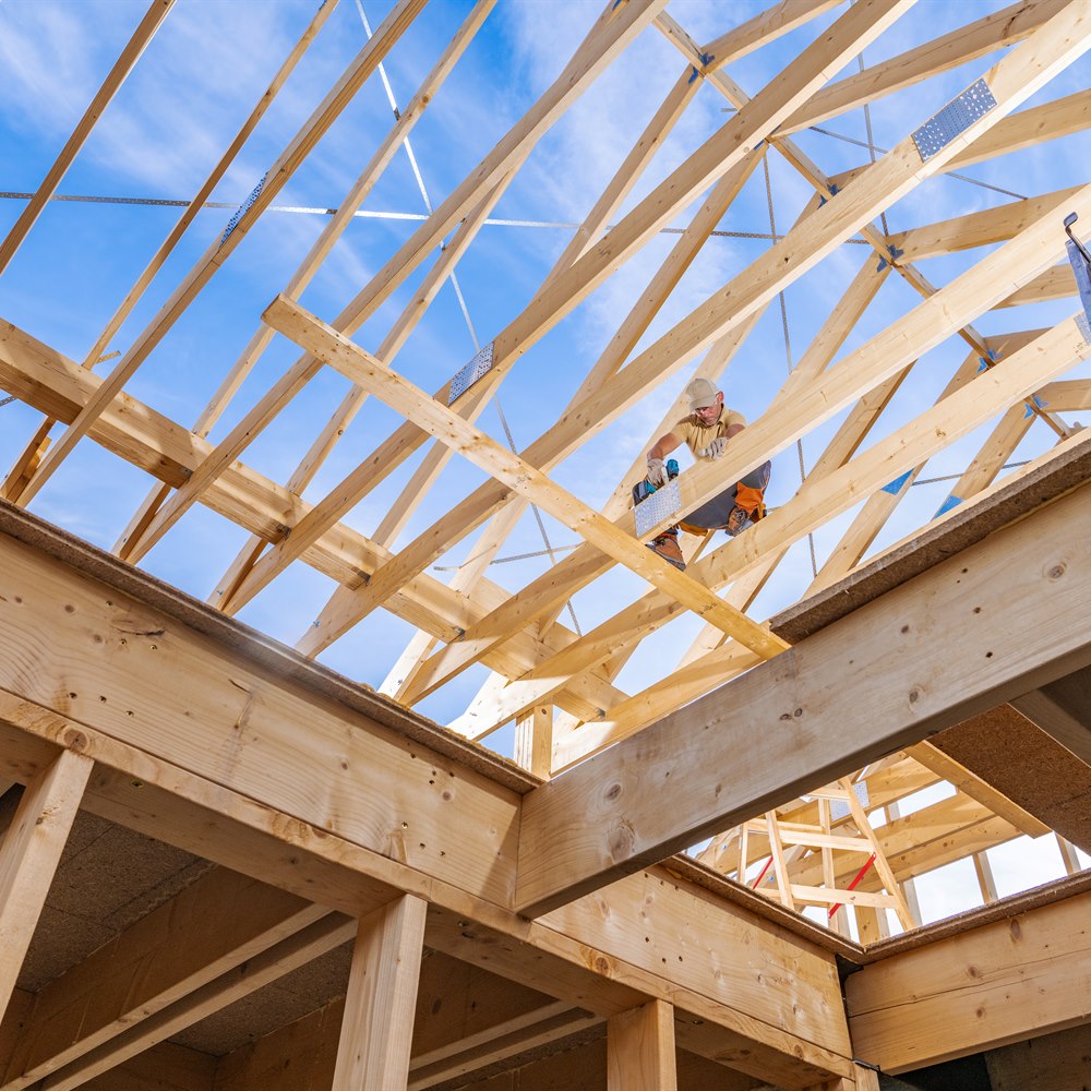 Construction worker building wooden house framework