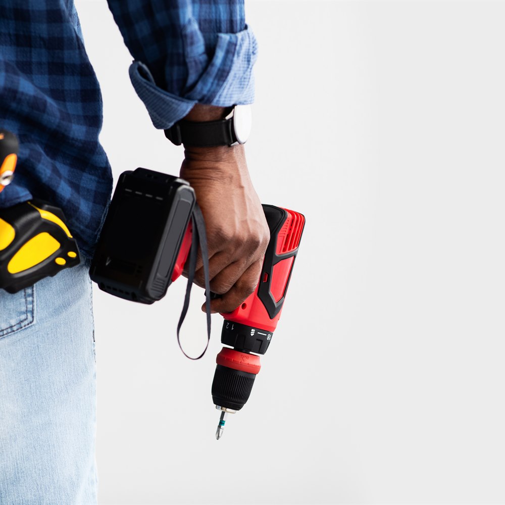 construction-worker-holding-drill-wearing-blue-pla Construction worker holding drill wearing blue