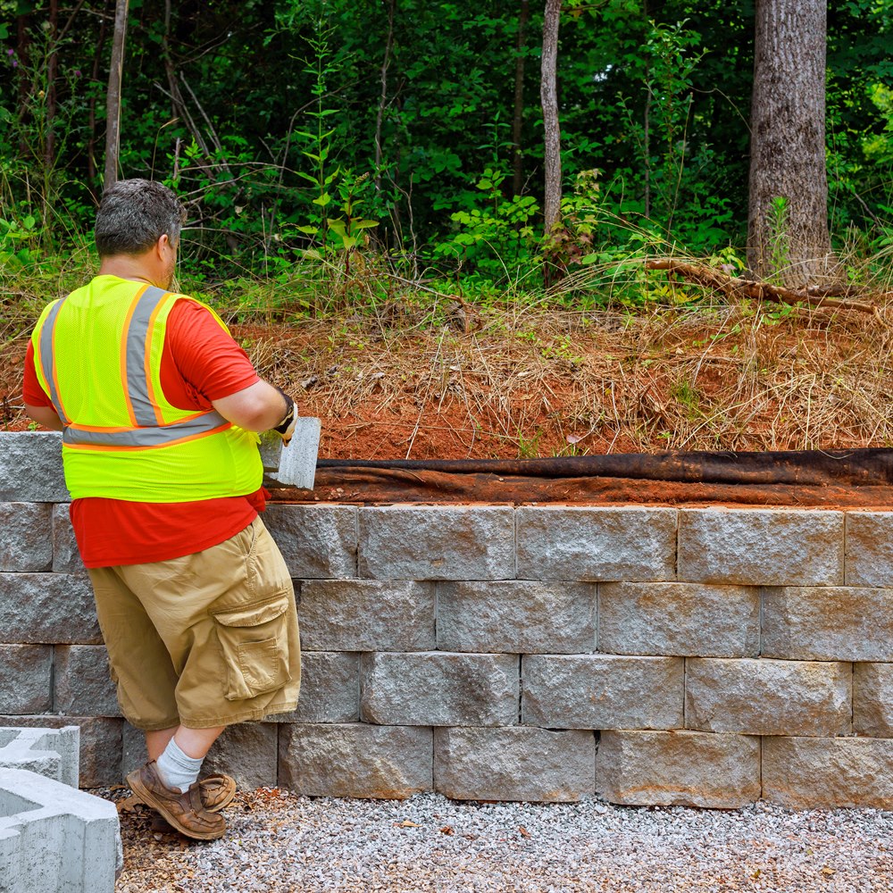 construction-worker-installing-a-stone-retaining Construction worker installing a stone retaining