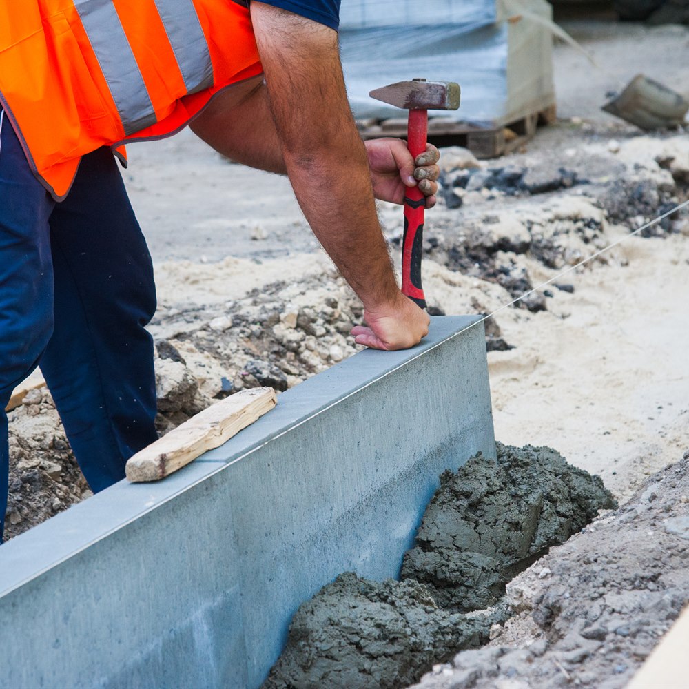 Construction worker installing concrete curb
