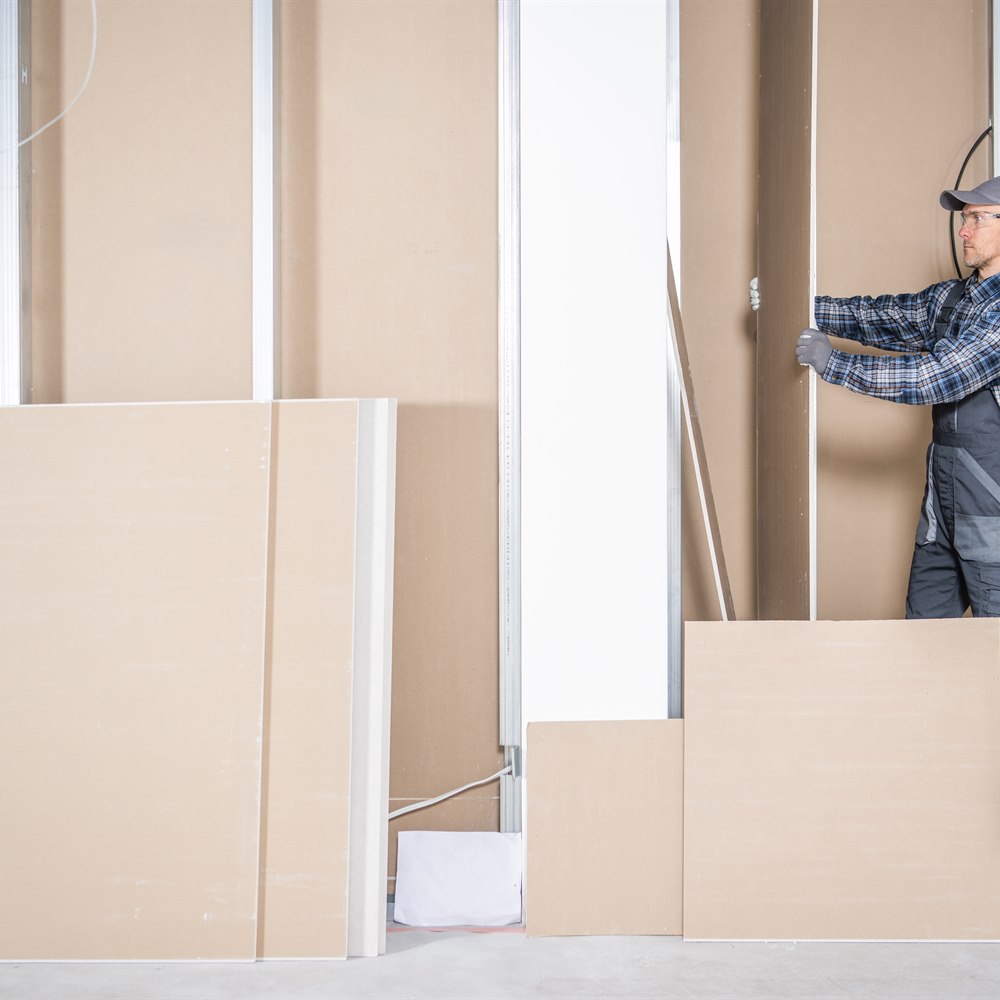 Construction worker installing drywall in building