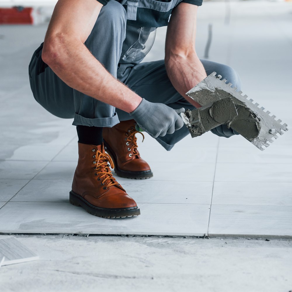 Construction worker installing tiles on the floor