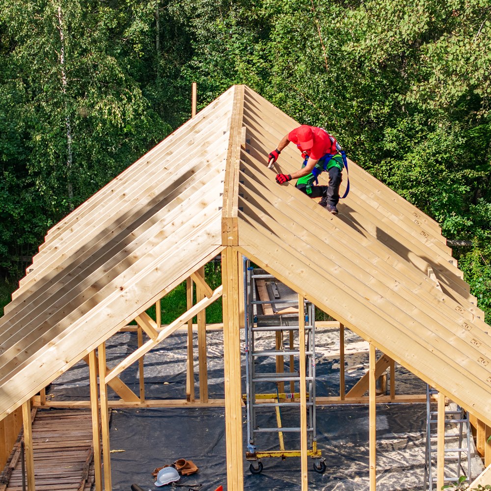 Construction worker installing wooden rafters