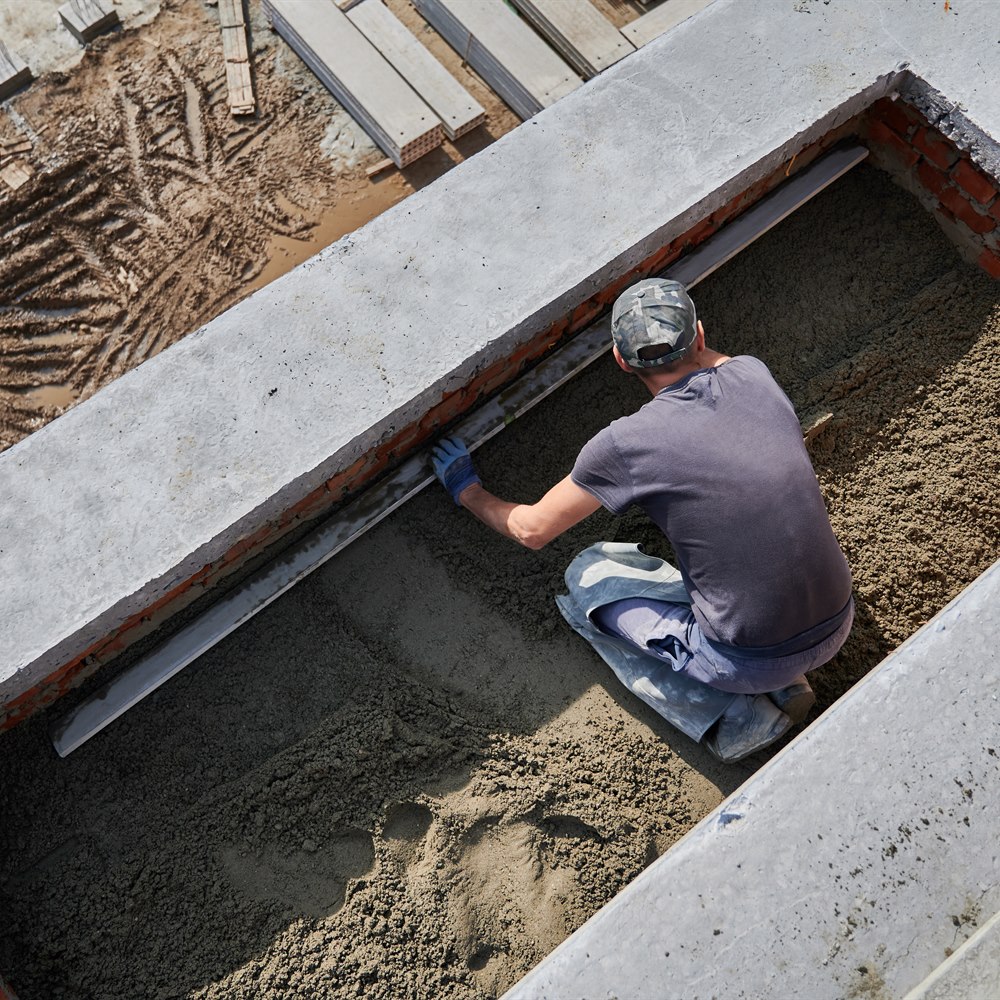 Construction worker smoothing gravel on new building