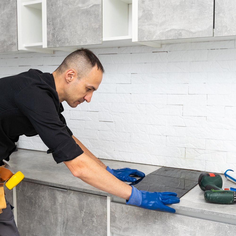 Contractor installing tile in modern kitchen
