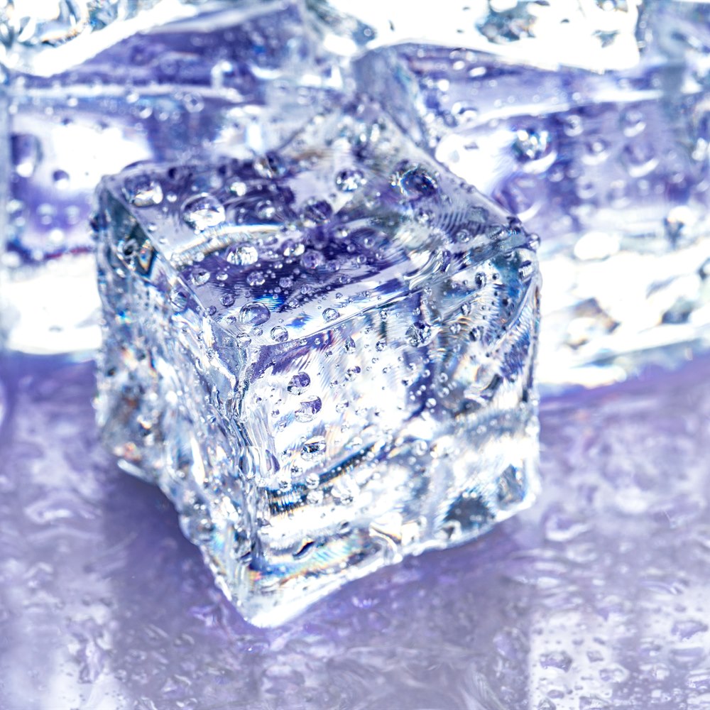 Crystalline ice cubes on a purple reflective surface