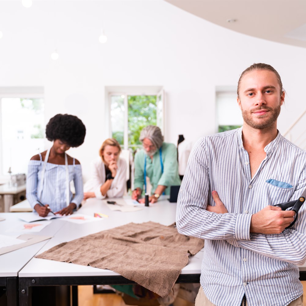Fashion designer posing in modern studio with team