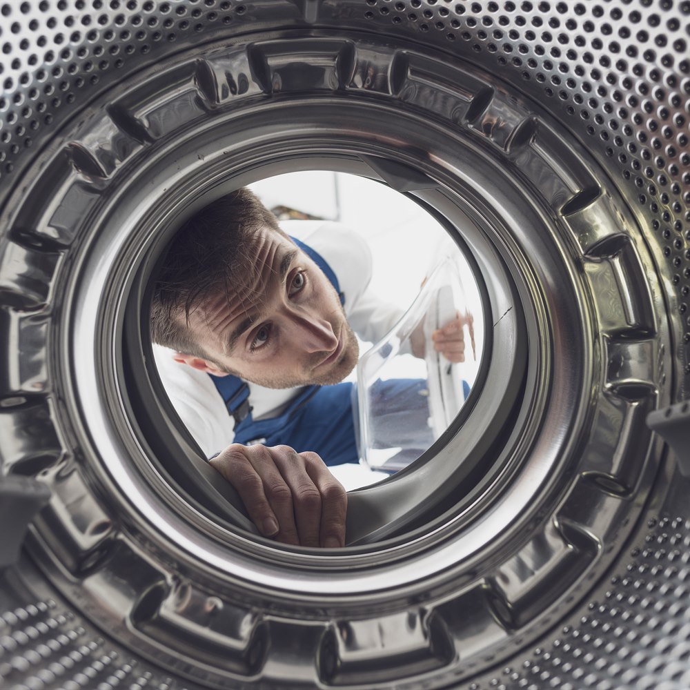 Focused man looks into washing machine drum
