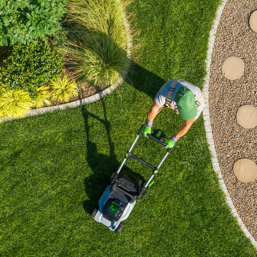 Gardener mowing backyard garden grass aerial view