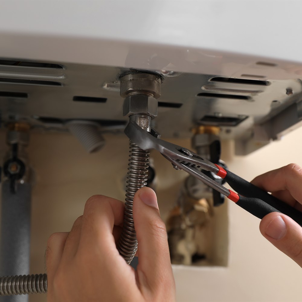 Hands adjusting gas pipes with pliers