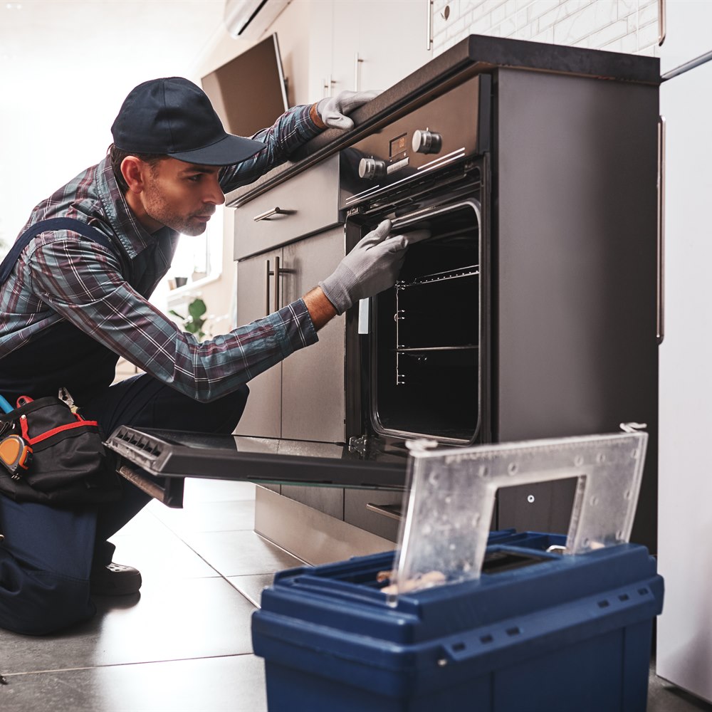 Handyman inspecting oven appliance repair in kitchen