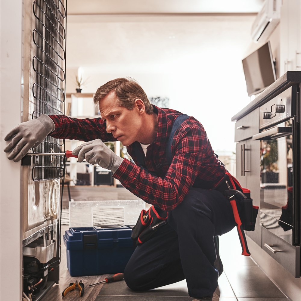 Handyman repairing appliance in kitchen