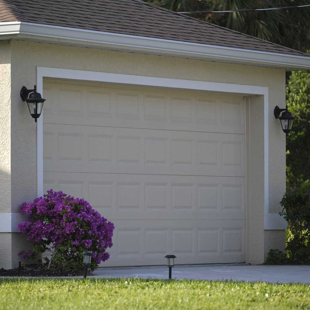 House exterior with garage door and purple flowers