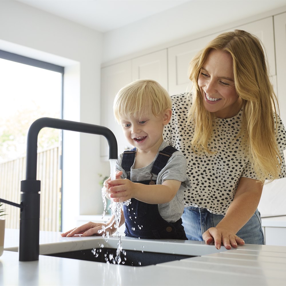 Laughing child playing at the sink with mom