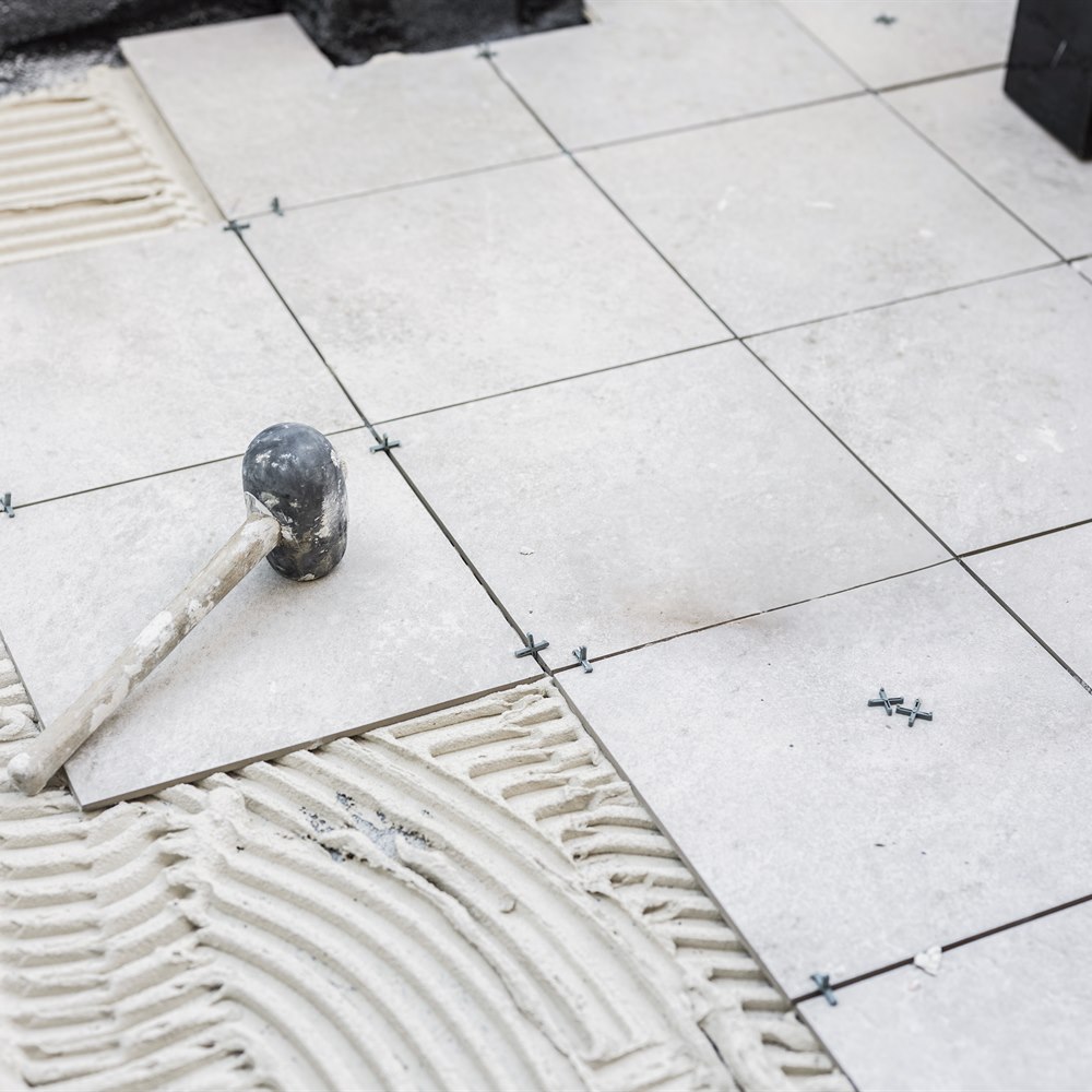 Laying ceramic tiles with cement and rubber hammer