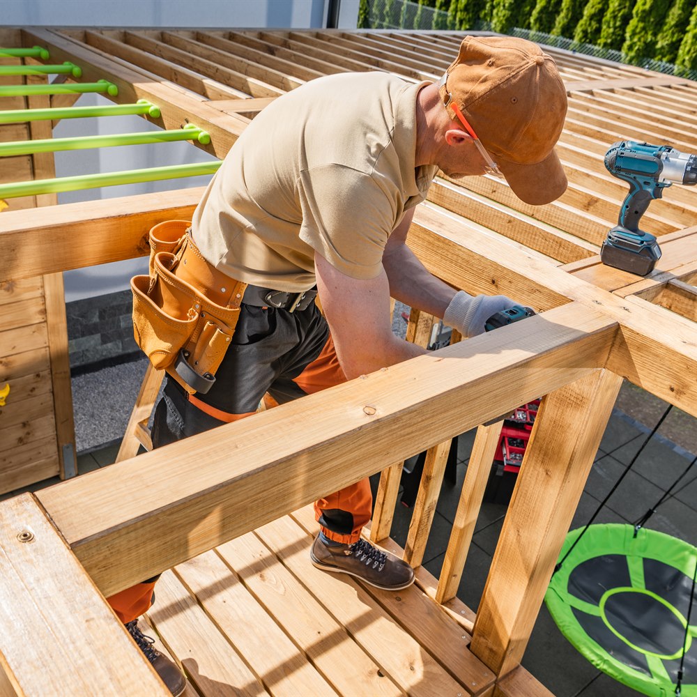 Male carpenter using power drill to build backyard
