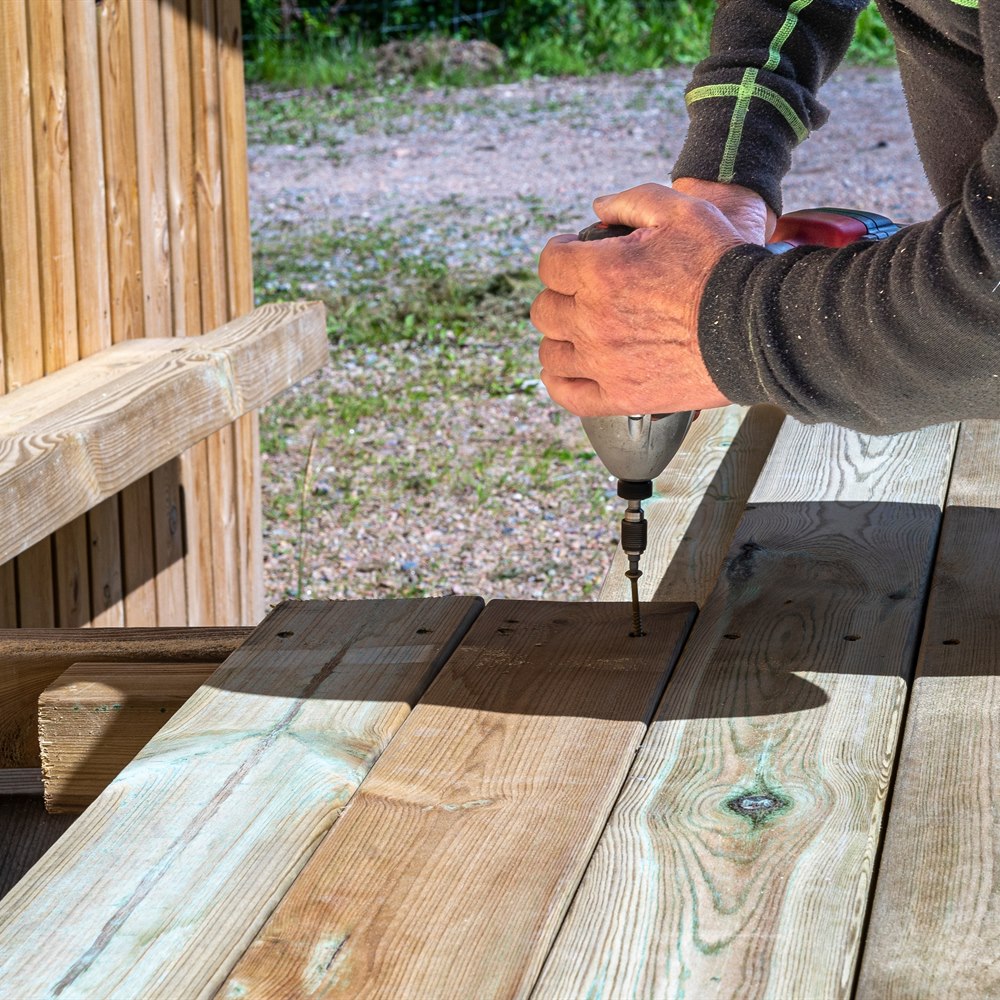 Man assembling wooden decking with a power drill