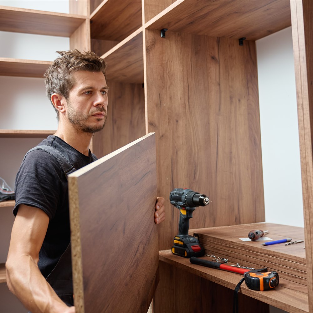 Man assembling wooden furniture indoors