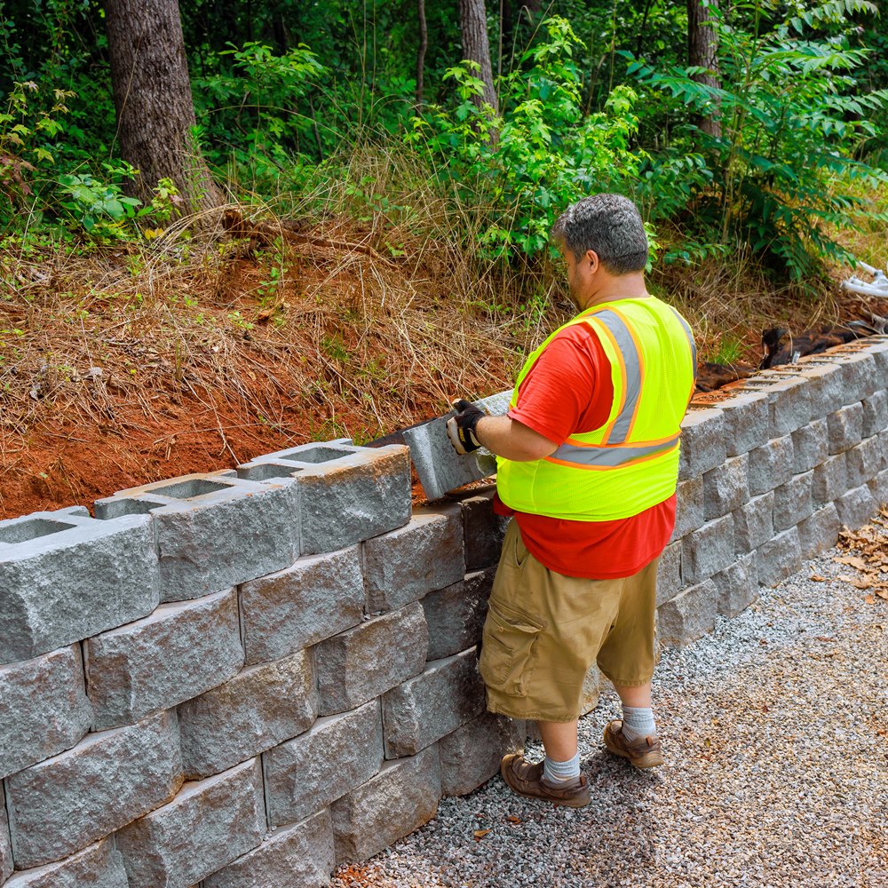 Man building retaining wall in wooded rural area