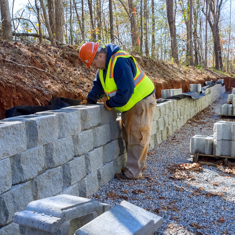 man-building-retaining-wall-with-concrete-blocks Man building retaining wall with concrete blocks