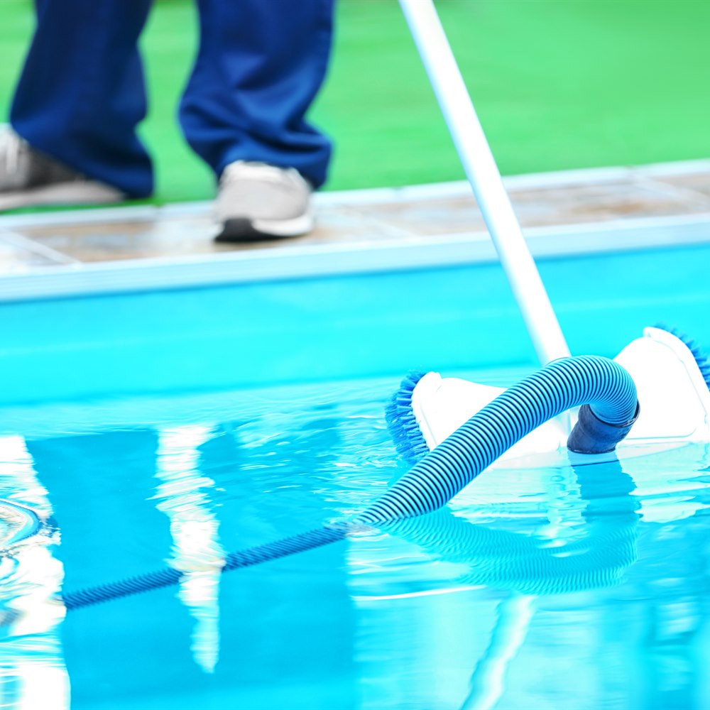 Man cleaning swimming pool with brush underwater