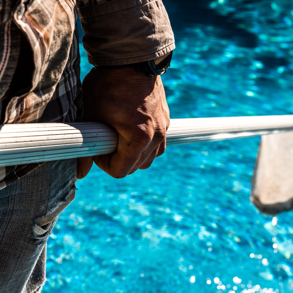 Man cleans a swimming pool