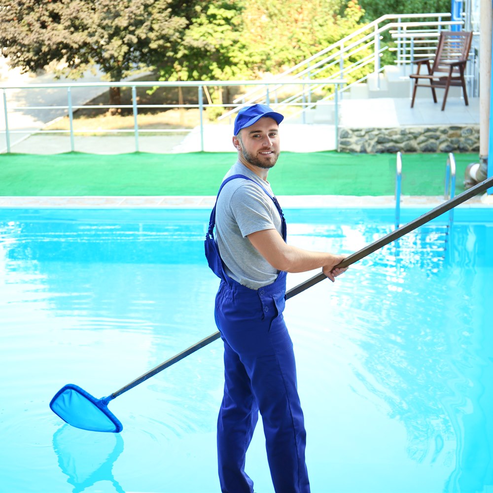 man-cleans-outdoor-pool-with-net-skimmer Man cleans outdoor pool with net skimmer