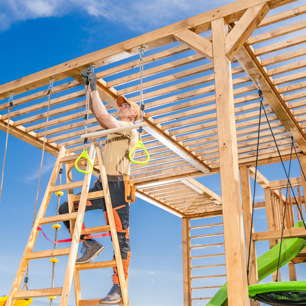 Man constructing wooden playground equipment