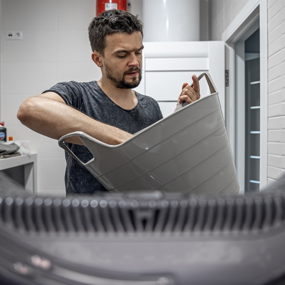 Man doing laundry in light clean bathroom