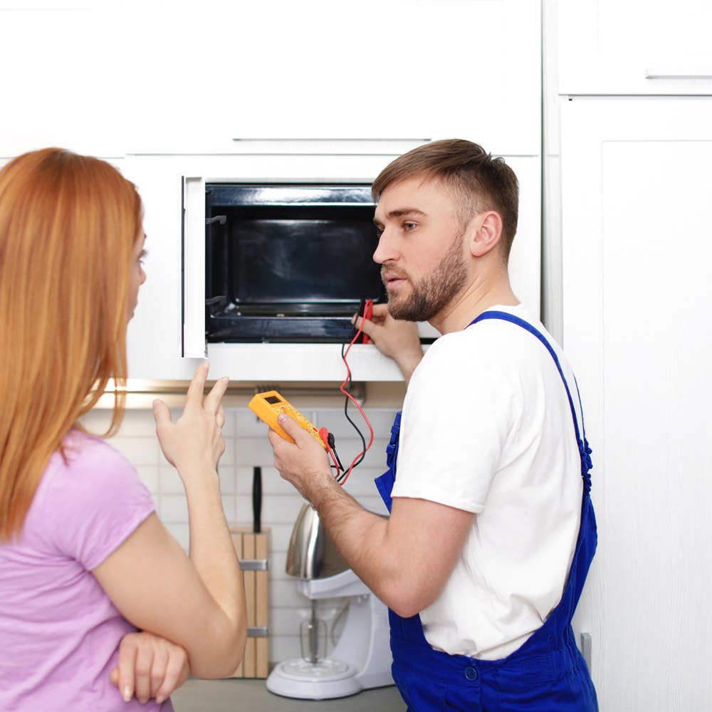 Man fixing appliance for woman in home kitchen