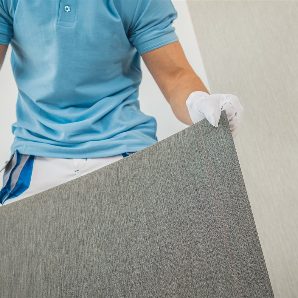 Man installing new textured grey wallpaper
